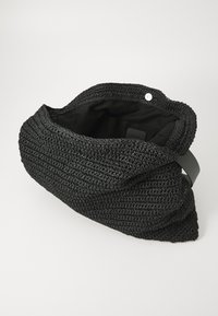 Black woven tote bag with a textured exterior, an open top, and a contrasting black fabric lining. Features a single black strap and snap closure.