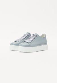 Lys blå lærersneakers med en hvid platformssål, der har bølgede kanter og satinbånd som snørebånd.