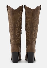 Hnědé kožené kovbojské boty se zdobným prošíváním; špičatá špička; šikmý kámen; blokový klín; zipy na boku; texturovaný povrch.
