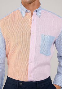 Camisa de botones a rayas que presenta secciones en naranja, rosa y azul, confeccionada en tejido ligero con un bolsillo en el pecho y un cuello de contraste.