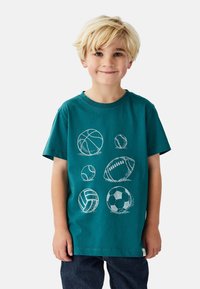 Blågrøn bomuld T-shirt med hvide omridsillustrationer af forskellige sportsbolde, herunder basketball, fodbold og volleyball.