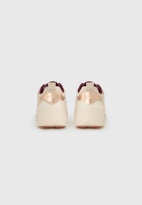 Baskets crème et bordeaux au design texturé et ergonomique. Accents métalliques sur le talon et la languette de tirage pour un enfilage facile.