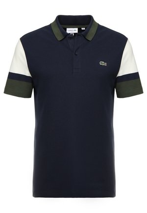 Polo bleu marine avec col vert, manches courtes blanches et vertes, et petit logo crocodile vert sur la poitrine.