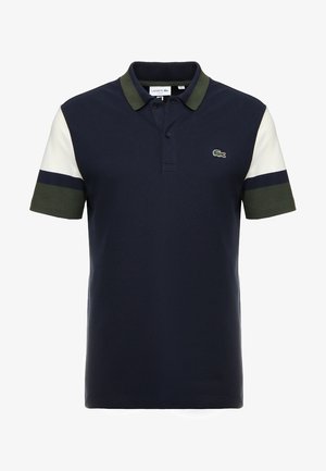 Polo bleu marine avec col vert, manches courtes blanches et vertes, et petit logo crocodile vert sur la poitrine.