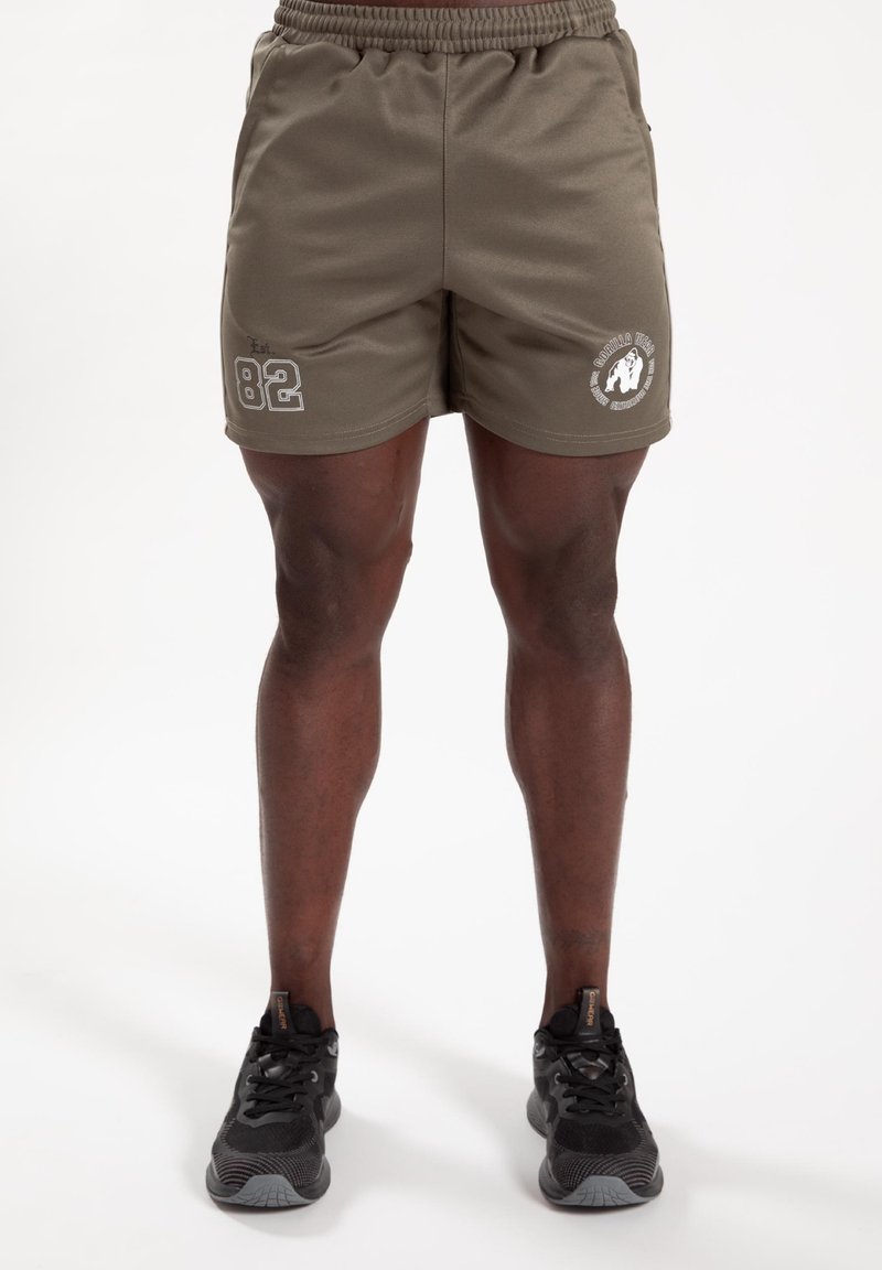 Olijfgroene sportieve shorts met een elastische tailleband. Heeft een wit grafisch logo en "82" bedrukt op de linkerdij. Textuurstof.