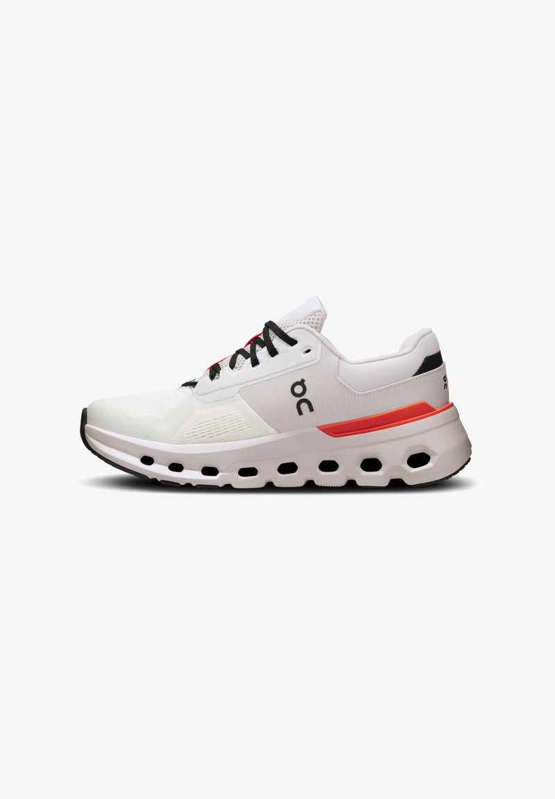 White running shoe with mesh upper, black laces, and red accents; features a thick sole with circular cutouts for cushioning.