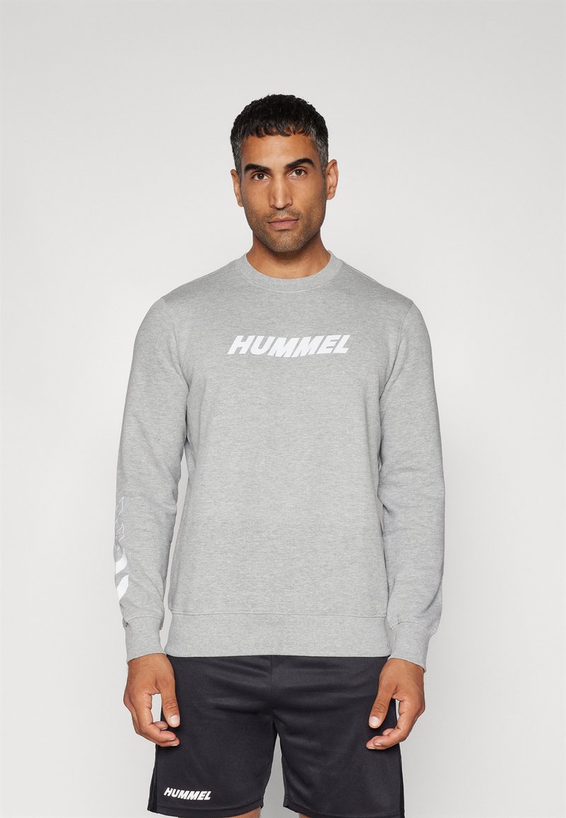 Grijze sweatshirt met lange mouwen van katoenmix, met een groot wit "HUMMEL" logo op de borst en strepen op de mouwen.