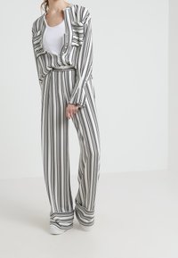 Randig loungedress i svart och vitt med en löst sittande topp med fickor och vida byxor, tillverkad i ett mjukt och lätt tyg.