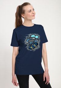 Námořnická modrá bavlněná tričko s grafikou skateboardisty v světle modré barvě a šedými akcenty, což vytváří dynamický design.