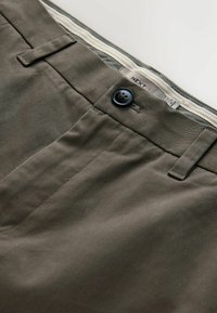 Chino-uri khaki dintr-o țesătură fină de twill; au un nasture negru, bucle pentru burtieră și buzunare laterale discrete; aspect curat și croit.