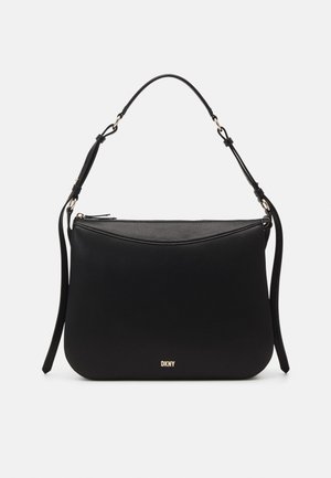 Bolso de hombro DKNY de cuero negro con correa ajustable y logo en tono dorado en la parte delantera sobre fondo blanco.
