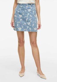 Falda de mezclilla con silueta ajustada, color azul claro y bordado floral en blanco. Presenta una cintura de media altura y un dobladillo recto.