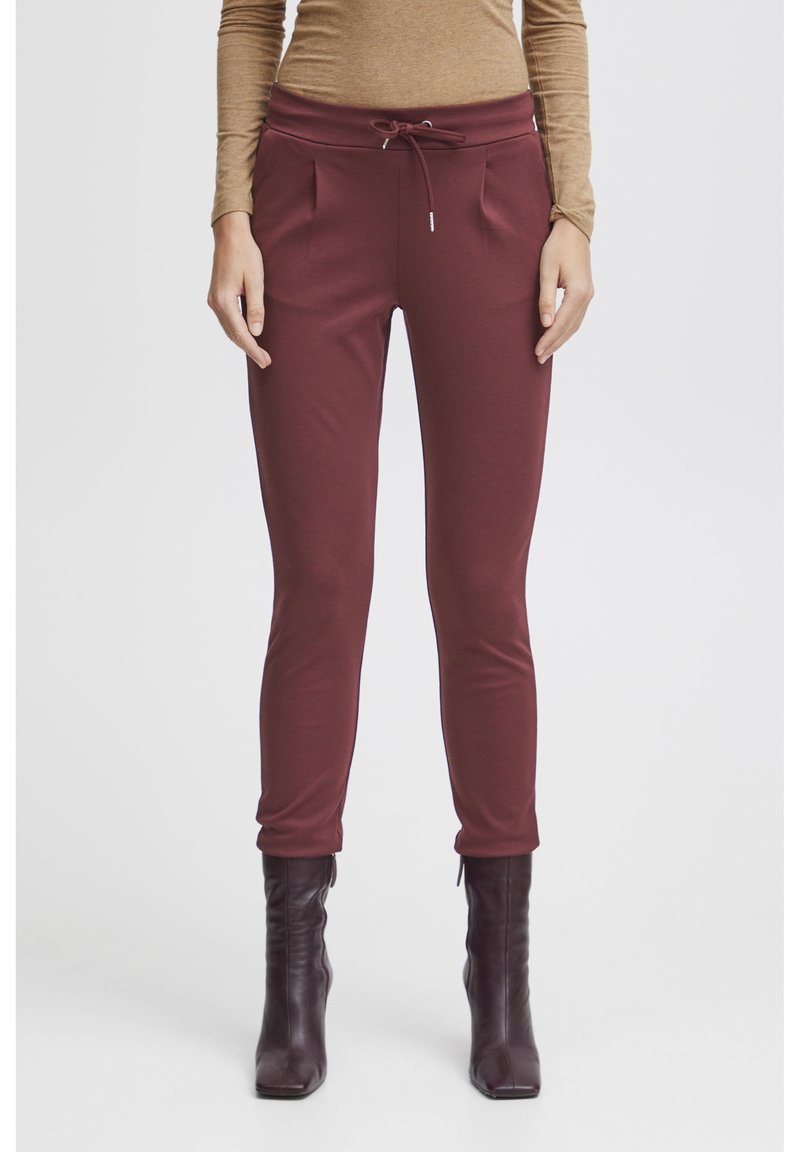 Burgundyröda sweatpants med dragsko i midjan, sidofickor och avsmalnande ben, tillverkade av mjukt bomullsmaterial.
