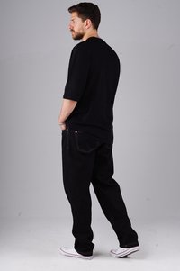 Black oversized t-shirt with short sleeves, paired with black loose-fit jeans and white sneakers. Minimal design, no visible patterns or logos.