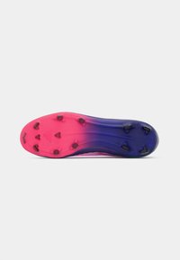 Suela de zapatilla deportiva, que presenta un degradado de rosa a púrpura, con una superficie texturizada y seis tacos negros para tracción.