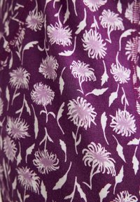 Paarse stof met een herhaald wit bloemenpatroon met gestileerde bloemen en bladeren, met een zachte textuur.