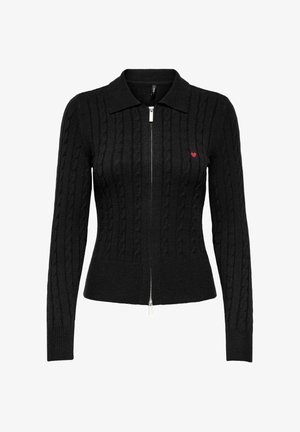 Juodas megztinis su kabelių raštu, užtrauktuku ir apykakle. Kairėje pusėje yra mažas raudonas širdelės detalė.