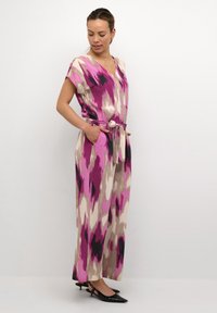 Vestido maxi multicolor con escote en V, mangas cortas y cintura ceñida con cinturón. La tela presenta un patrón abstracto en rosa, beige y negro.