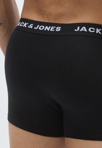 Svarta boxershorts i mjukt material med resårmidja som har etiketten "JACK & JONES" i vitt tryck.