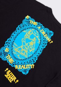 T-shirt nera con una grafica blu e gialla. Il design rappresenta uno scheletro e una figura, incorniciati da un bordo simile a pizzo, con del testo.