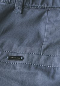 Tessuto blu con sottili righe verticali, caratterizzato da un orlo cucito e un piccolo etichetta metallica con la dicitura “Street One” fissata vicino alla vita.