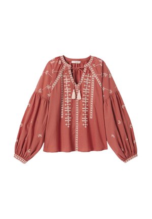 Blouse couleur rouille avec motifs géométriques blancs brodés, manches longues bouffantes, et décolleté en V avec lien et pompons.