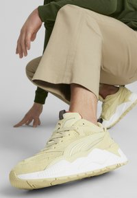 Sneakers w kolorze żółtym i kremowym, wykonane z zamszu i siateczki, z teksturowanymi podeszwami i zaokrąglonym kształtem.