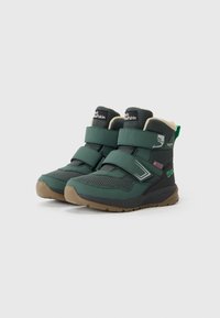 Green winter boots with a textured fabric upper, two Velcro straps, cushioned interior, and a brown rubber outsole. Features branding on the tongue.