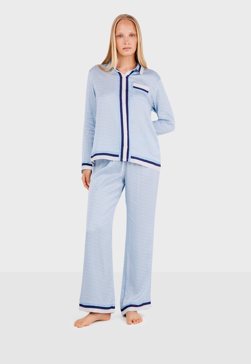 Light blue pajama set with a geometric pattern, featuring a button-up shirt and wide-leg pants with navy trim and accents. Soft fabric texture.