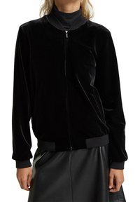 Czarna aksamitna kurtka bombowiec z zamkiem z przodu, ściągaczami na mankietach i u dołu. Miękka w dotyku, o luźnym kroju i minimalistycznym designie.