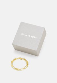 Kuldne metallketi käevõru, millel on ristkülikukujulised lingid. Kliendile on saadaval hõbe-hall kast, millel on valgete tähtedega "MICHAEL KORS".