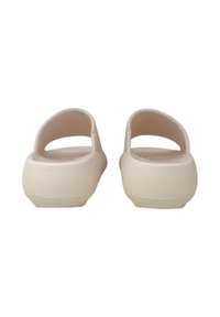 Zoccoli color crema chiaro con una superficie liscia e opaca. Apertura sul retro e sui lati con una forma arrotondata e un leggero motivo di grip sulla suola.