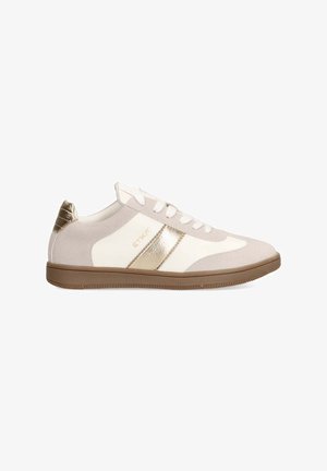 Zapatilla beige y blanca con acentos dorados, materiales de ante y cuero, punta redondeada y suela de goma con un patrón texturizado.