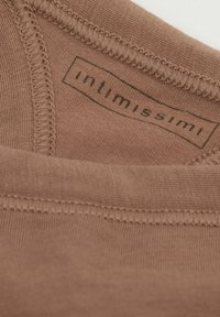 Bruine stof met een gladde textuur, met een label waarop "intimissimi" staat. De stiksel rond de rand is zichtbaar.