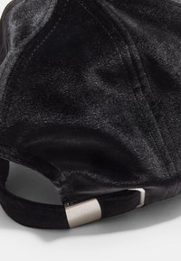 Black velvet cap featuring a curved brim, textured surface, and a metal adjustable strap at the back for securing fit.