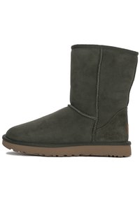 Donkergroene suède enkelboots met een ronde neus, verticale stiksels en een bruine rubberen zool. De schacht is lichtjes getextureerd.
