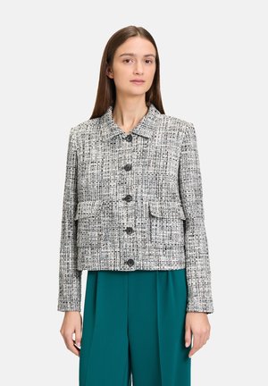 Veste courte tissée noir et blanc avec un col, fermeture par boutons sur le devant, deux poches avant et un motif texturé.