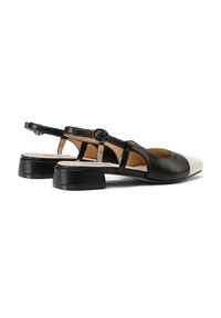 Scarpe slingback in pelle nere e beige con punta arrotondata, tacco basso a blocco e cinturino alla caviglia regolabile. Texture liscia e design minimal.