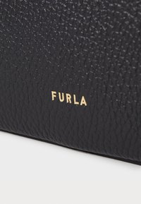 Zwarte leren tas met een gestructureerd oppervlak; bevat een gouden "FURLA"-logo. Eenvoudig, gestructureerd ontwerp zonder aanvullende versieringen.