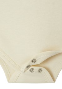 Detailaufnahme des cremefarbenen Babystramplers mit drei teilweise festgeknöpften Metall-Druckknöpfen auf dem weichen Stoff.