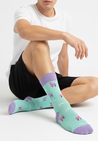 Turkis sokker med lilla accenter, med forskellige lama-mønstre og hvide sky-motiver. Bomuldsblanding, over ankellængde.