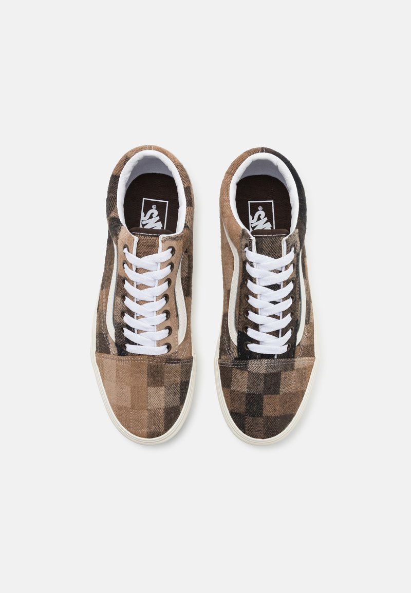 Baskets à carreaux brunes avec un dessus en tissu texturé, des lacets blancs et une bande latérale noire contrastante, avec une semelle en caoutchouc blanche.