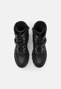 Bottes cheville en cuir noir avec ferrures métalliques, lacets ajustables, col rembourré et semelles en caoutchouc texturées pour une meilleure adhérence.