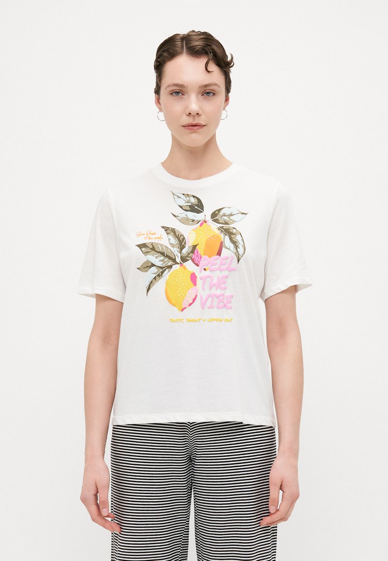 T-shirt bianco a maniche corte con stampa grafica di limoni e testo "PEEL THE VIBE." Presenta una vestibilità rilassata e materiale in cotone morbido.