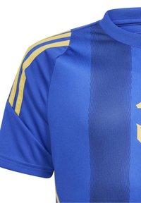 Sininen urheilujersey, jossa on keltaiset raidat harteilla, teksturoituja pystysuoria viivoja keskellä, ja korostettu keltainen logo edessä.