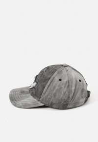 Casquette en denim gris avec un design usé, dotée d'une visière incurvée et d'une sangle réglable. Comprend des œillets noirs pour la respirabilité.