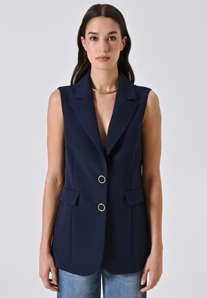 Ärmelloser, navyfarbener Blazer mit Reverskragen, zwei vorderen Taschen und goldfarbener Knöpfen. Glatter Stoff mit einer taillierten Passform.