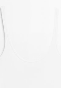 Close-up of the upper part of a plain white sleeveless tank top with a scoop neckline and wide shoulder straps.
