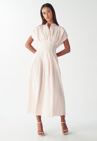 Vestido maxi de color rosa claro con rayas verticales blancas, mangas cortas abullonadas, cierre de botones y una cintura ajustada que se convierte en una falda completa y fluida.