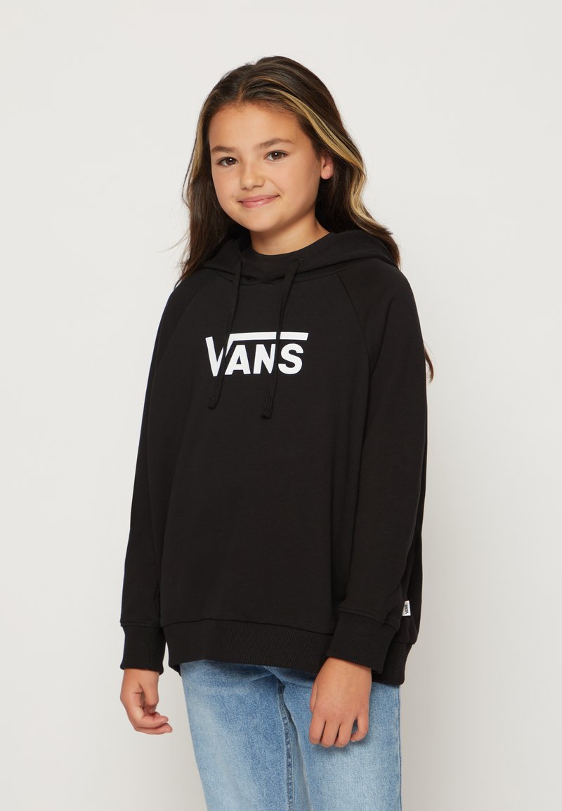 Felpa nera con cappuccio e logo bianco "VANS", caratterizzata da una vestibilità comoda, polsini a coste e spacchi laterali, abbinata a jeans blu chiaro.